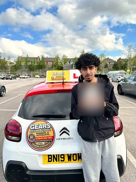 A learner in a black jacket holds a pass certificate behind a white Citroën C3