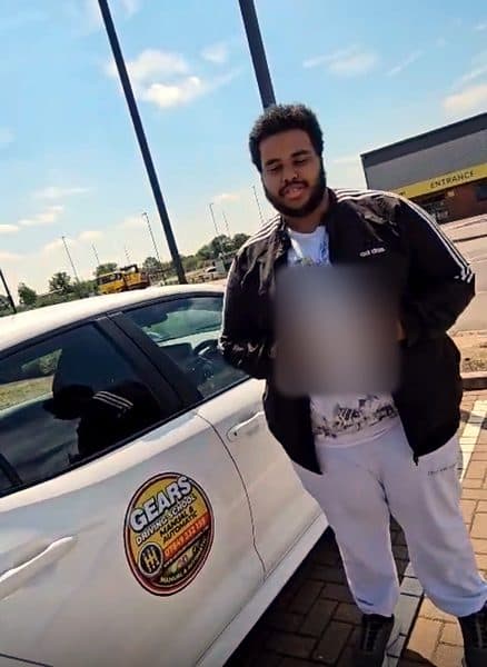 A learner in a black tracksuit top holds a pass certificate beside a white Gears car